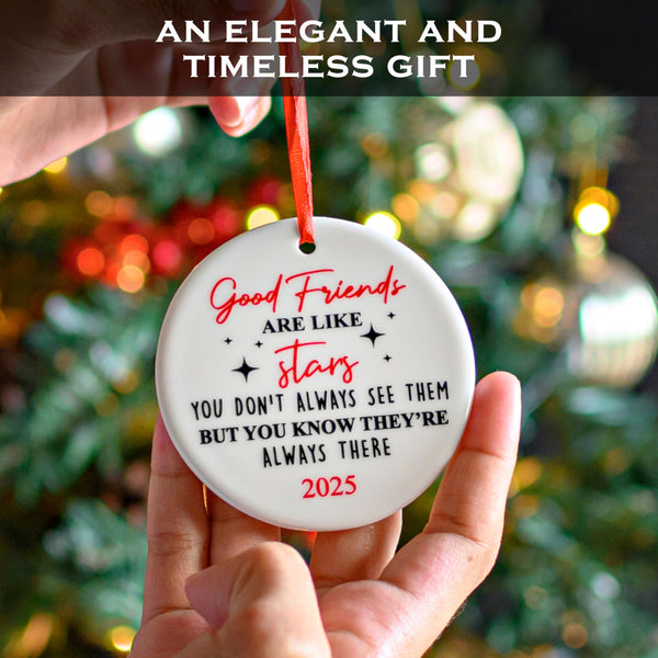 Decorative ornament with a quote about friends, held in front of a Christmas tree.