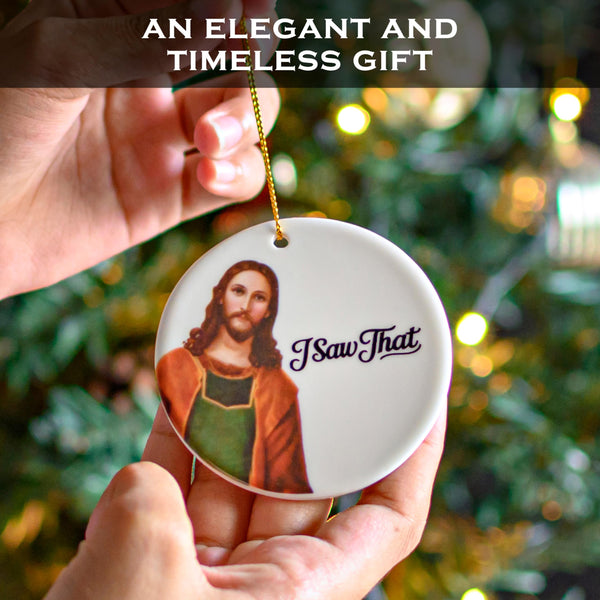 Decorative Christmas ornament with a religious figure and 'I Saw That' text, held in front of a blurred Christmas tree.