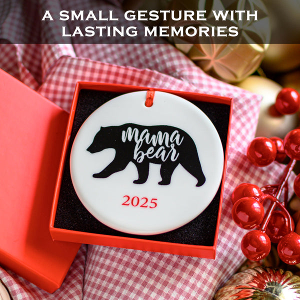 Decorative ornament with 'mama bear' and '2025' text, placed in a red box on a checkered fabric background.