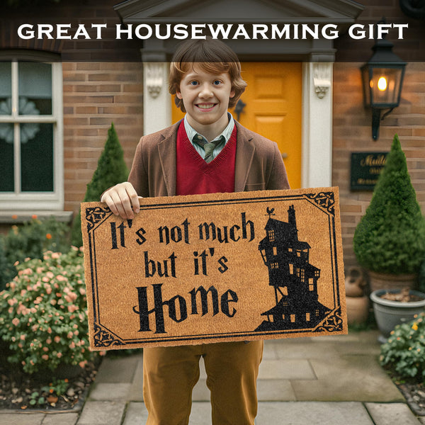 Person holding a doormat with 'It's not much but it's Home' text in front of a house.
