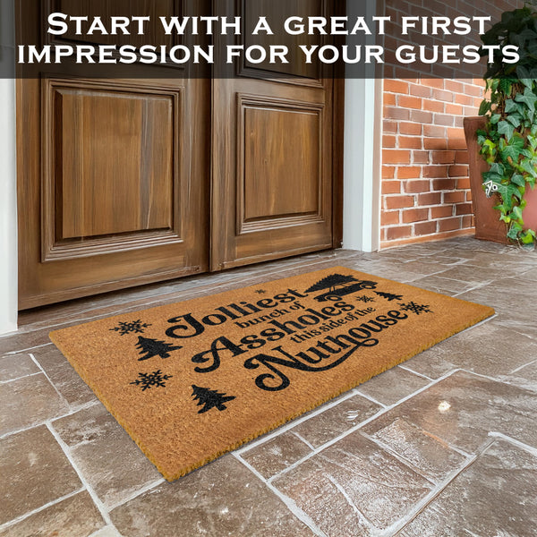 Doormat with humorous text on a stone patio in front of wooden doors.