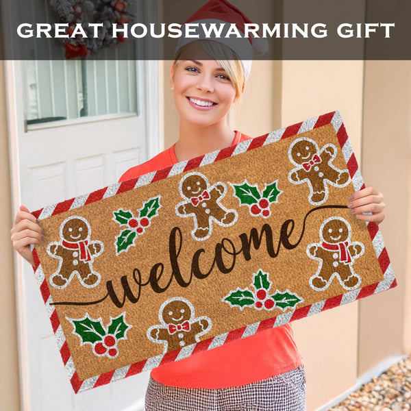 Person holding a decorative doormat with gingerbread men and 'welcome' text, suitable for housewarming gifts.