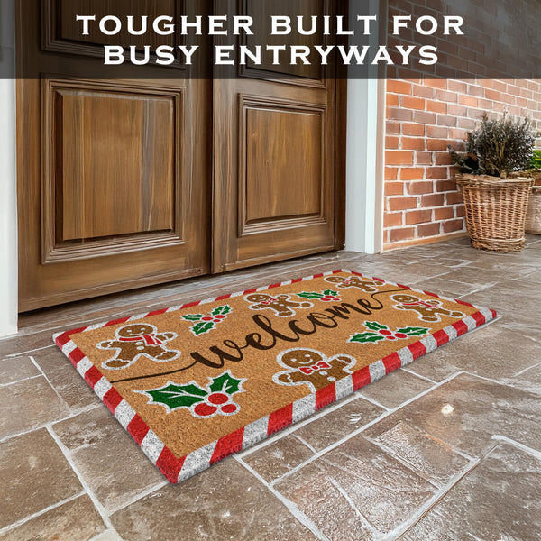 Decorative doormat with gingerbread design on a stone floor in front of wooden doors.