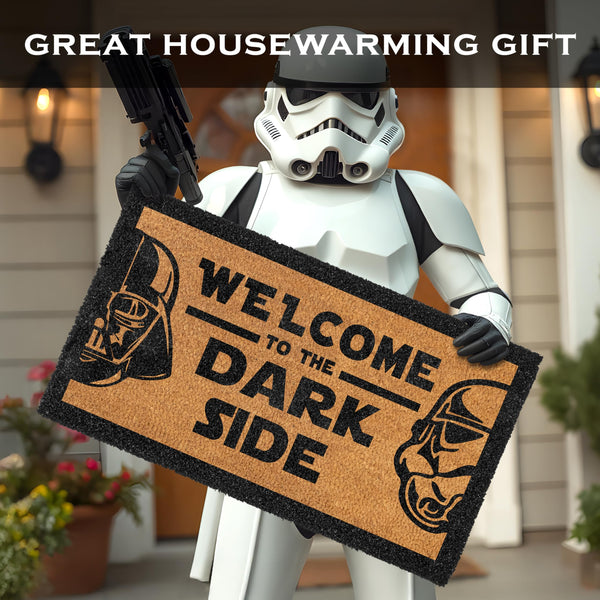 Person in stormtrooper costume holding a doormat with 'Welcome to the Dark Side' text, with 'Great Housewarming Gift' text at the top.