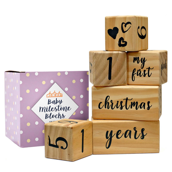 A set of wooden blocks with numbers and words printed on them, used as a baby milestone prop, displayed alongside its packaging box.