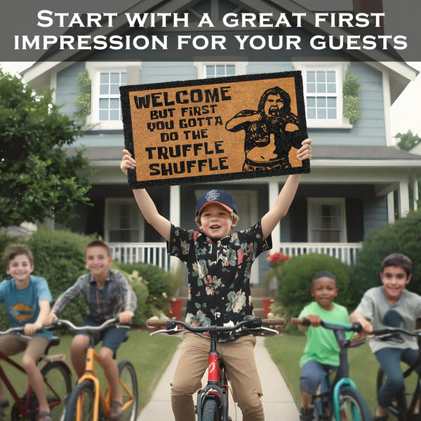Child holding a doormat with a humorous design in front of a house, with children on bikes in the background.