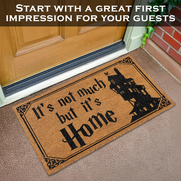 Doormat with 'It's not much but it's Home' text and a house silhouette on a wooden door.