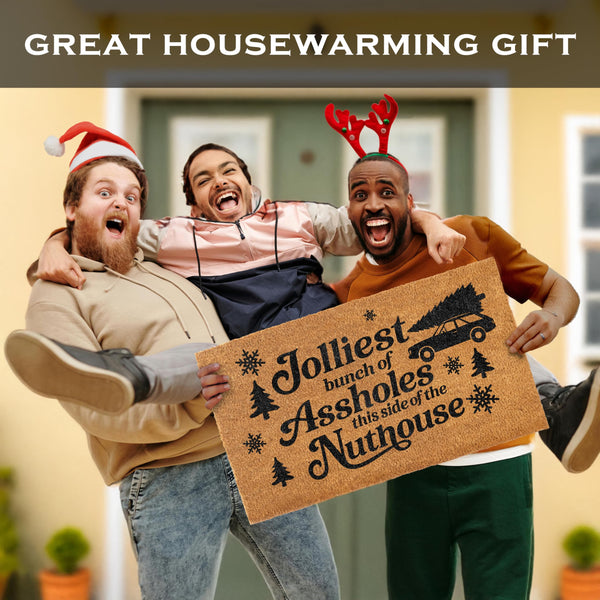 Three people holding a doormat with humorous text, with the text 'GREAT HOUSEWARMING GIFT' at the top.