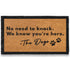 Doormat with text 'No need to knock. We know you're here. The Dogs' on a white background